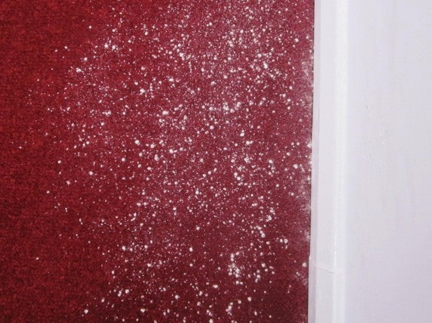Red carpet with white dust particles before vacuuming