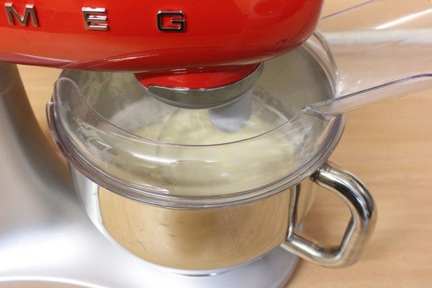 Red Smeg stand mixer mixing ingredients in a kitchen.
