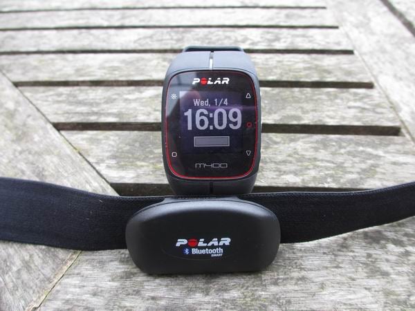 Polar M400 watch and heart rate sensor on wooden surface.