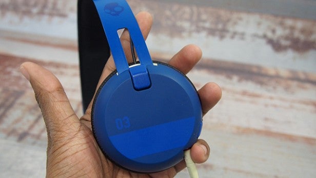 Hand holding blue Skullcandy Grind Wireless Headphone.