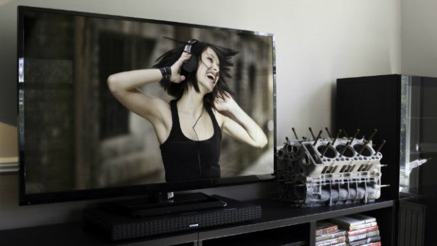 Otone Soundbase under TV with woman enjoying music on screen.