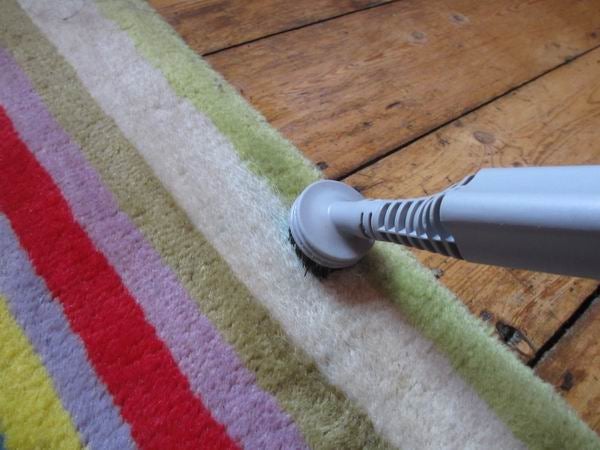 Vax S6S Home Pro steam cleaner in use on a colorful carpet.