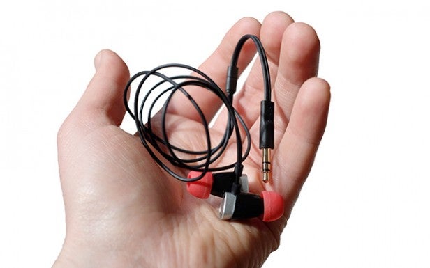 Hand holding a pair of wired in-ear headphones.