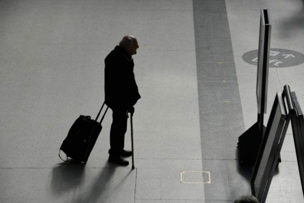 Man with luggage in dimly lit station, high contrast image.
