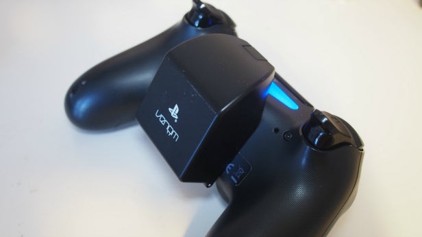 Venom rechargeable battery pack attached to PS4 controller.Venom PS4 rechargeable battery pack on dark background.