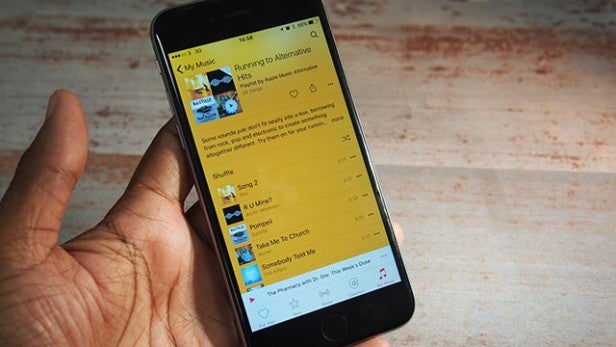 Hand holding iPhone displaying Apple Music app with playlist.