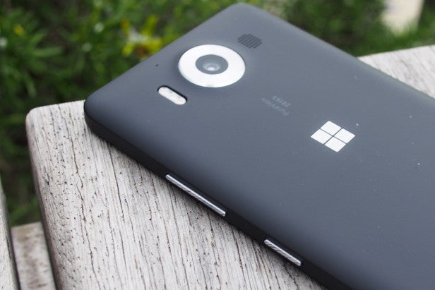 lumia950 29Smartphone with camera and Microsoft logo on wooden surface.