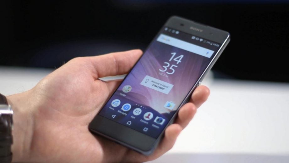 Hand holding Sony Xperia XA smartphone displaying home screen.