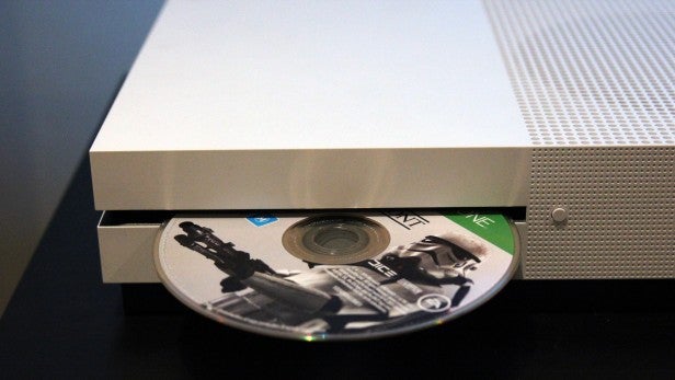 Xbox One S console with game disc on a black surface.