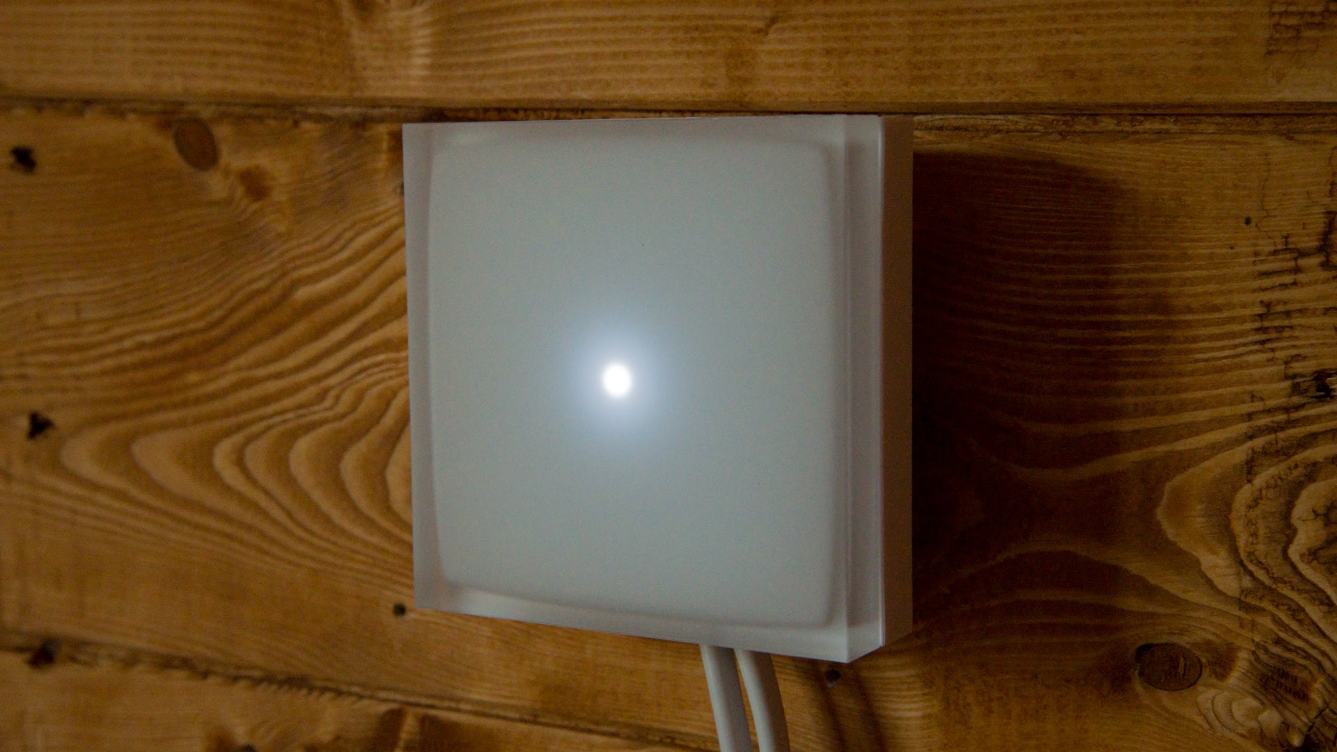 Netatmo Smart Thermostat mounted on wooden wall.
