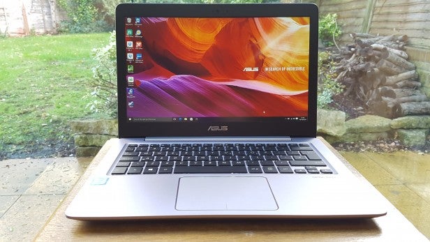 Asus ZenBook UX310UA 2Asus laptop on wooden table with screen displaying desktop wallpaper.