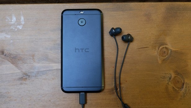 evo 27HTC smartphone charging with earbuds on wooden surface.