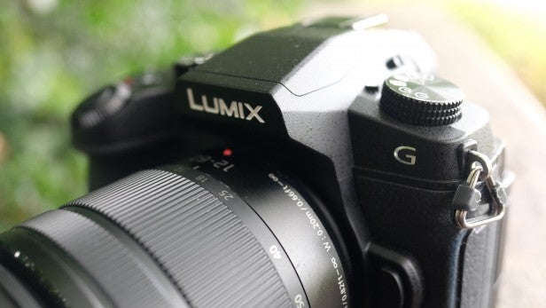 Panasonic G80Close-up of Lumix G camera with lens against blurred background.