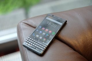BlackBerry KEYone smartphone on a textured brown surface.