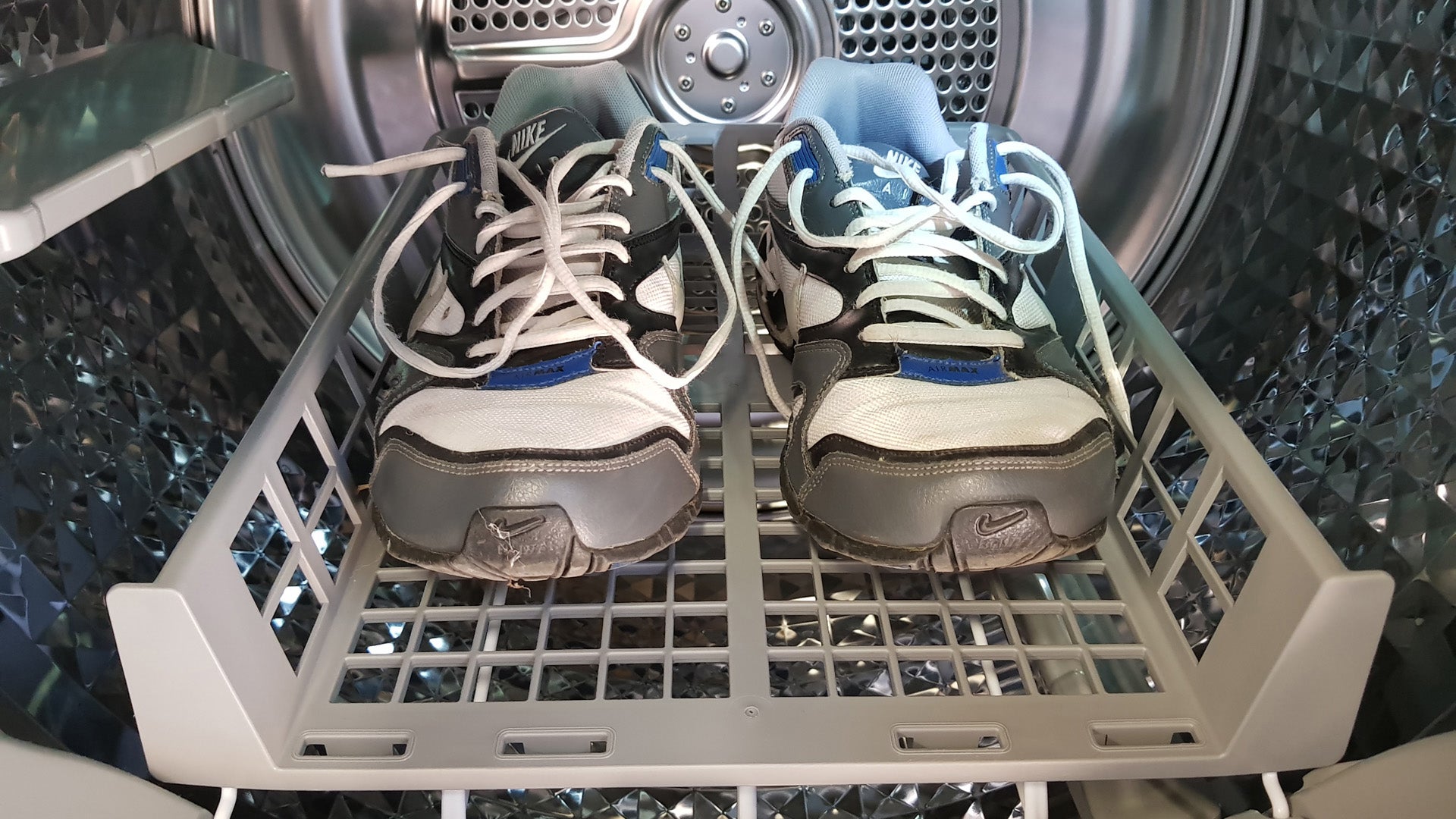 Sneakers drying inside Samsung tumble dryer with shoe rack.