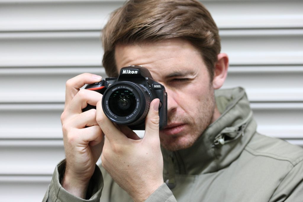 Man taking a photo with a Nikon D5600 camera.