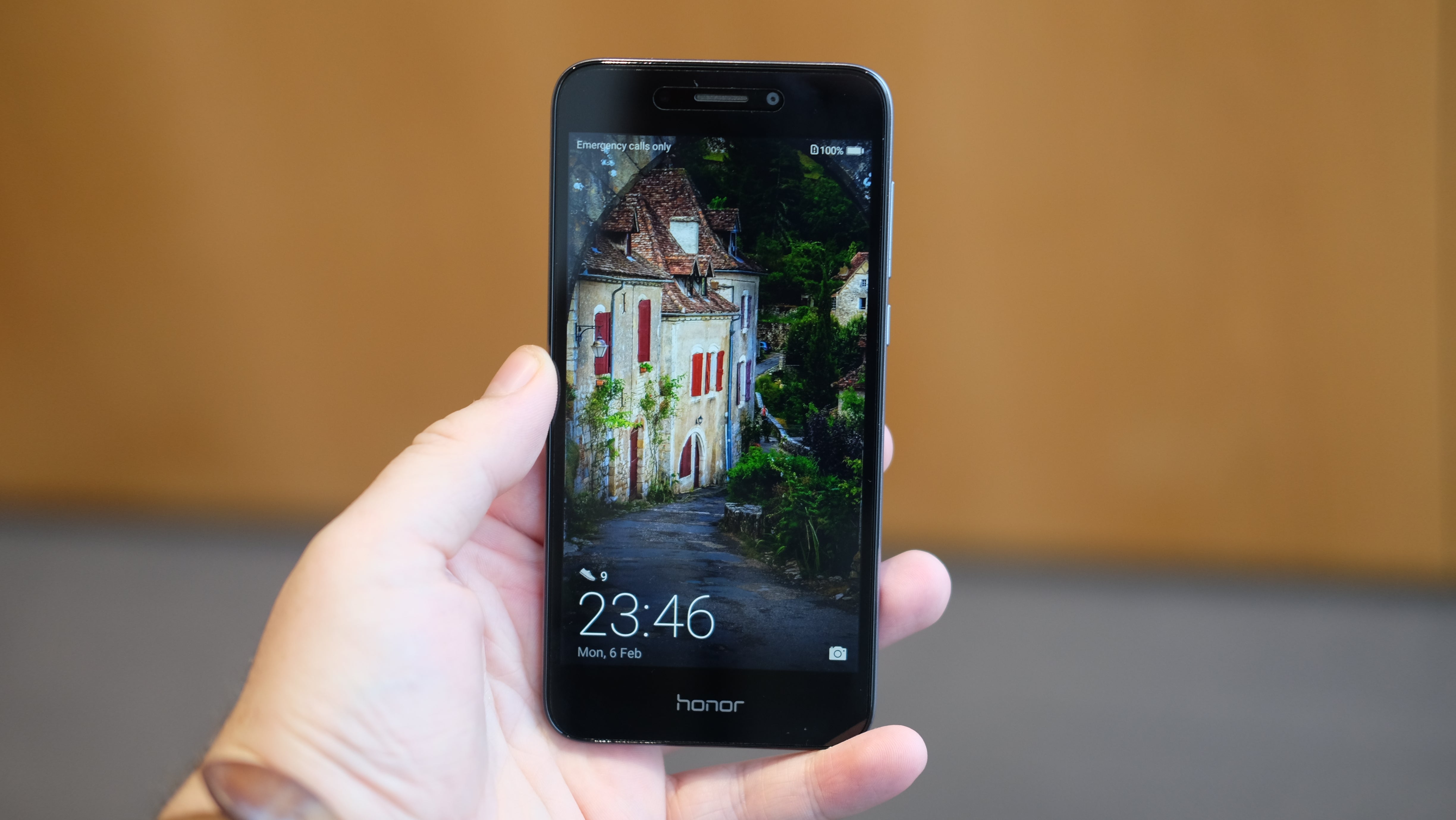 Hand holding Honor 6A smartphone displaying a wallpaper.