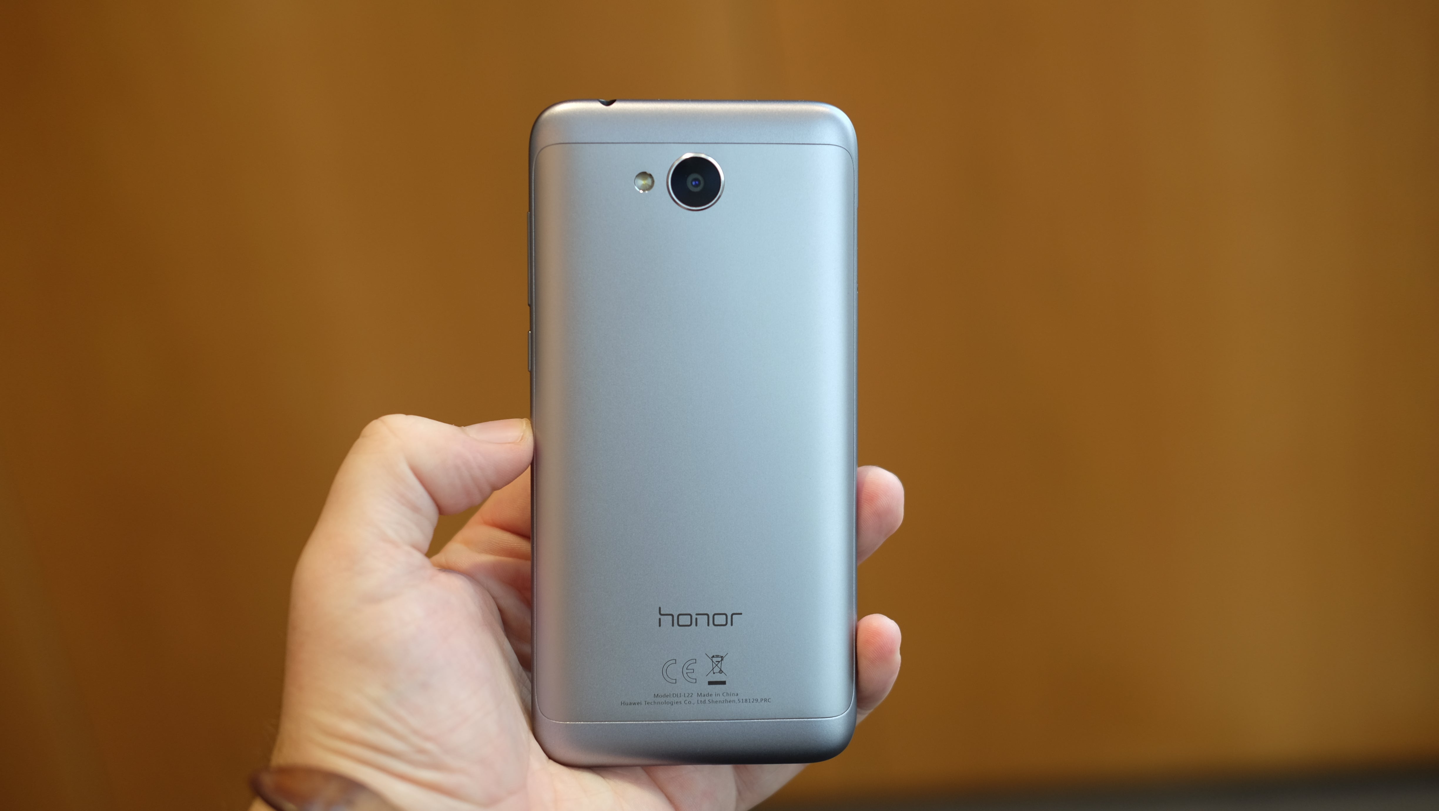 Hand holding Honor 6A smartphone showing rear view.