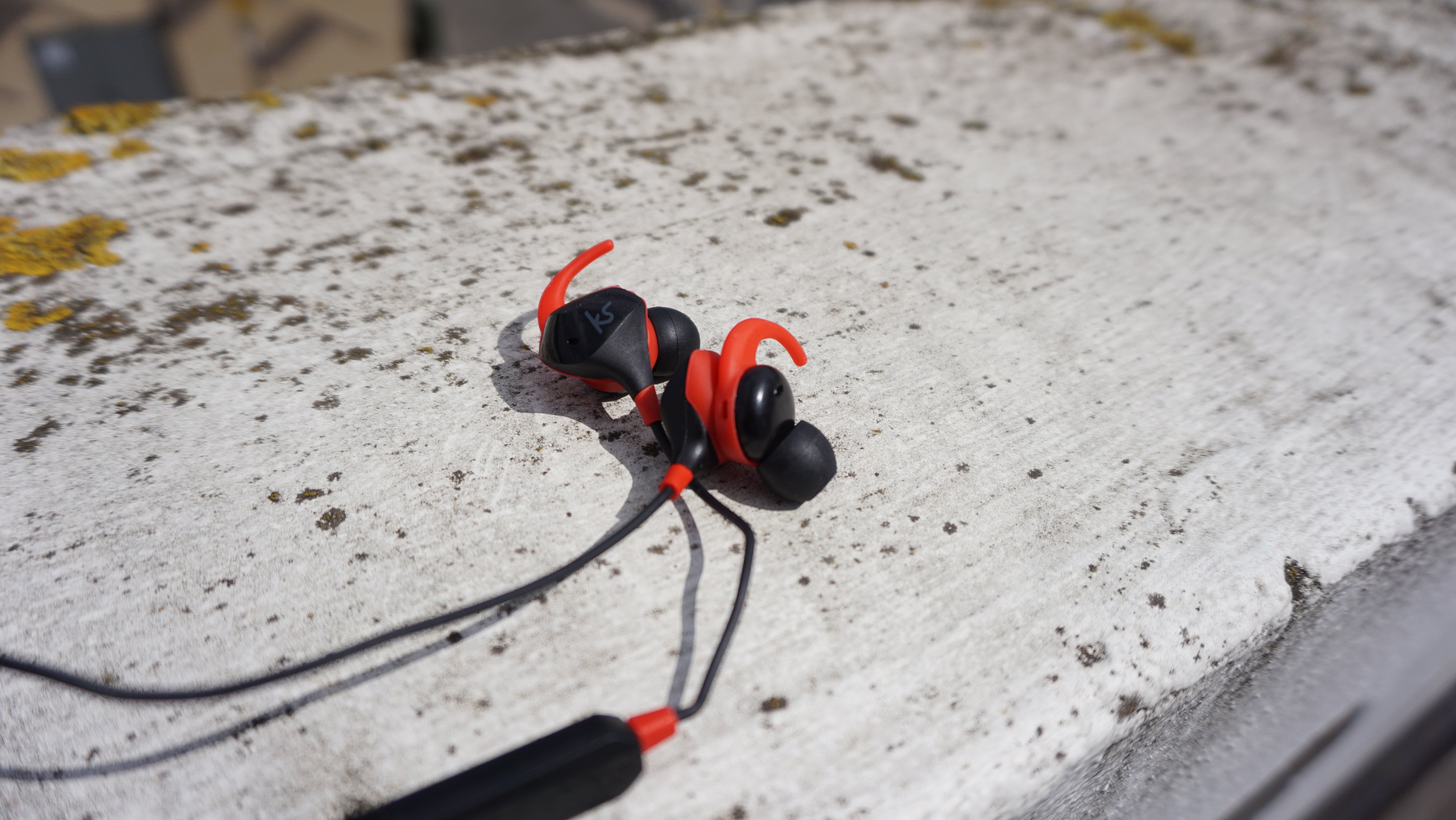 KitSound Immerse Active earphones on concrete surface.