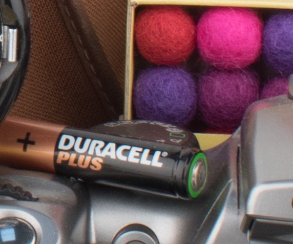 Close-up of Nikon D5600 with Duracell battery and colorful background.
