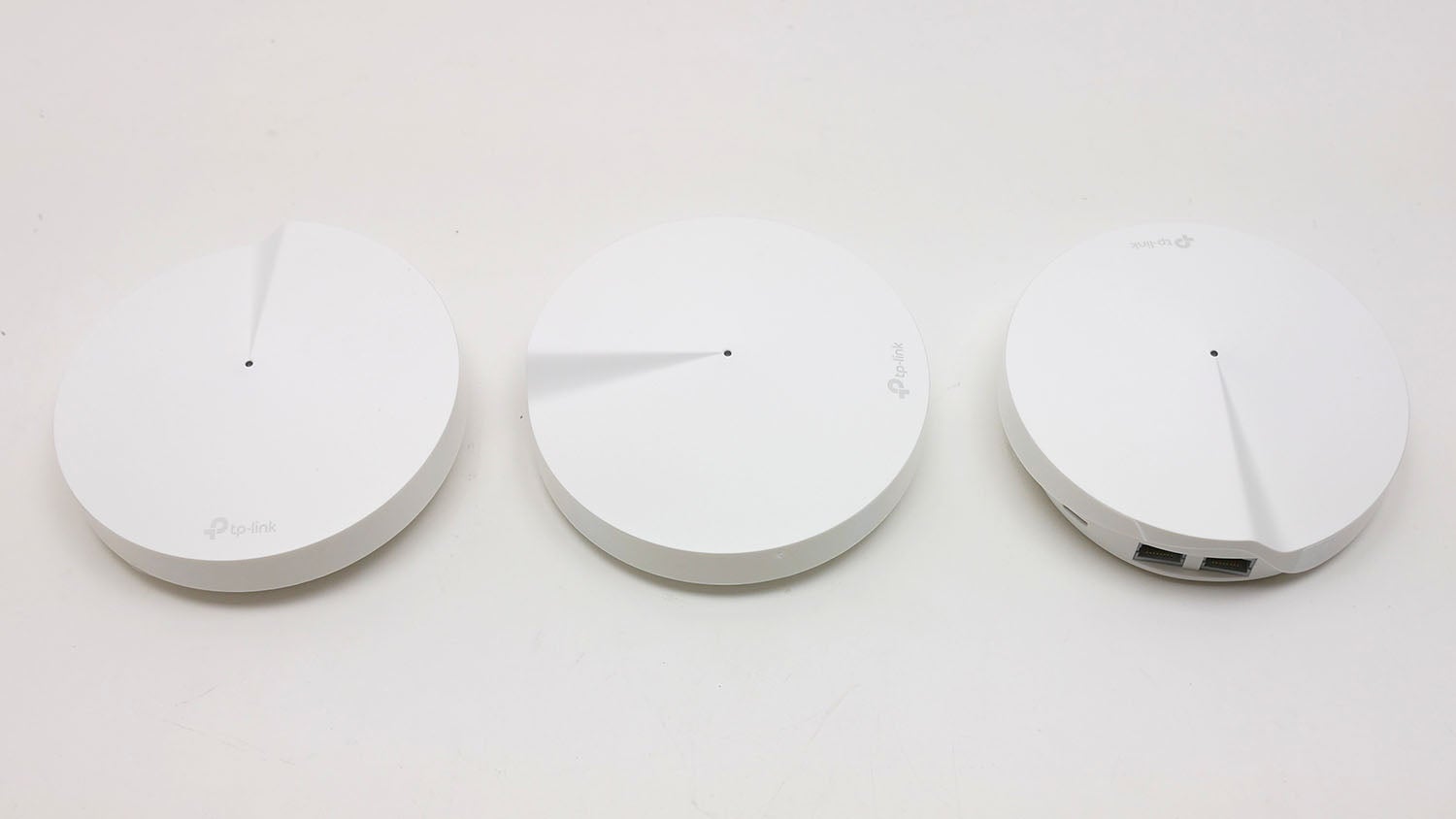 Three TP-Link Deco mesh Wi-Fi units on a white surface.