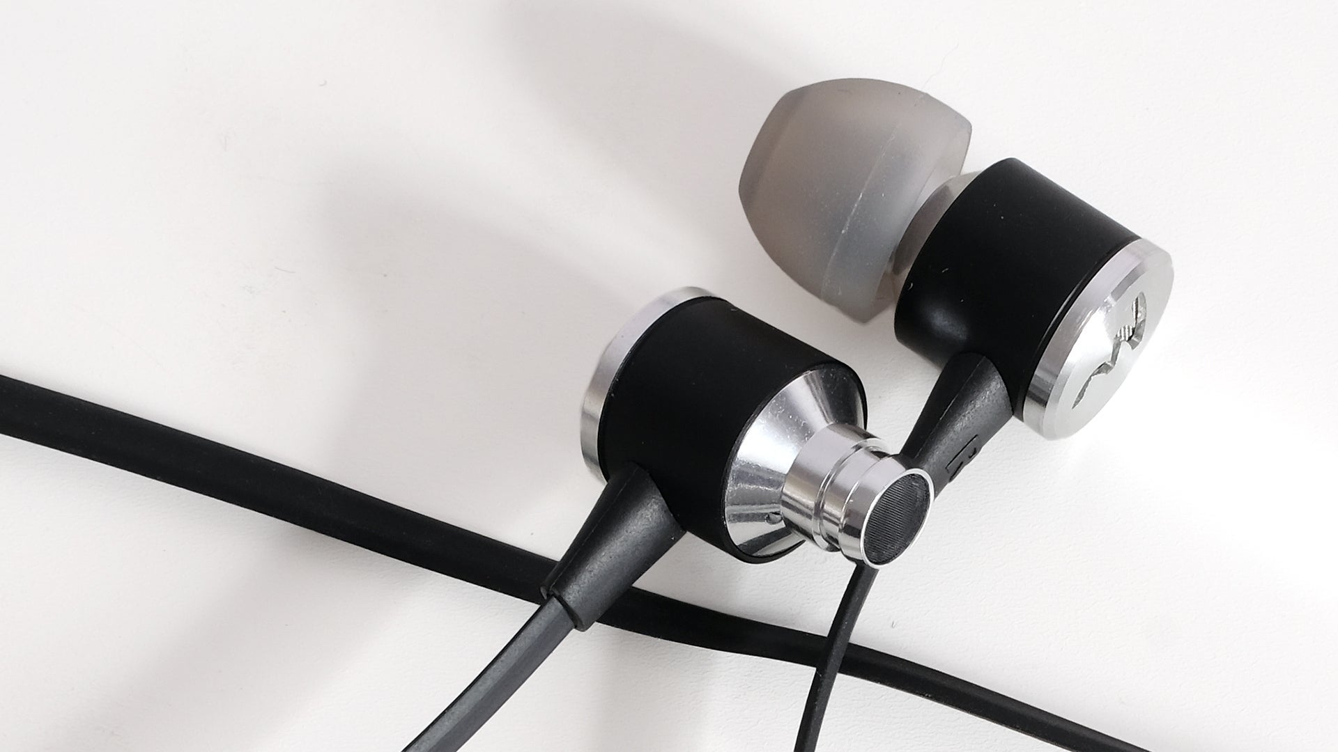 Close-up of Focal Spark Wireless earphones on white background.