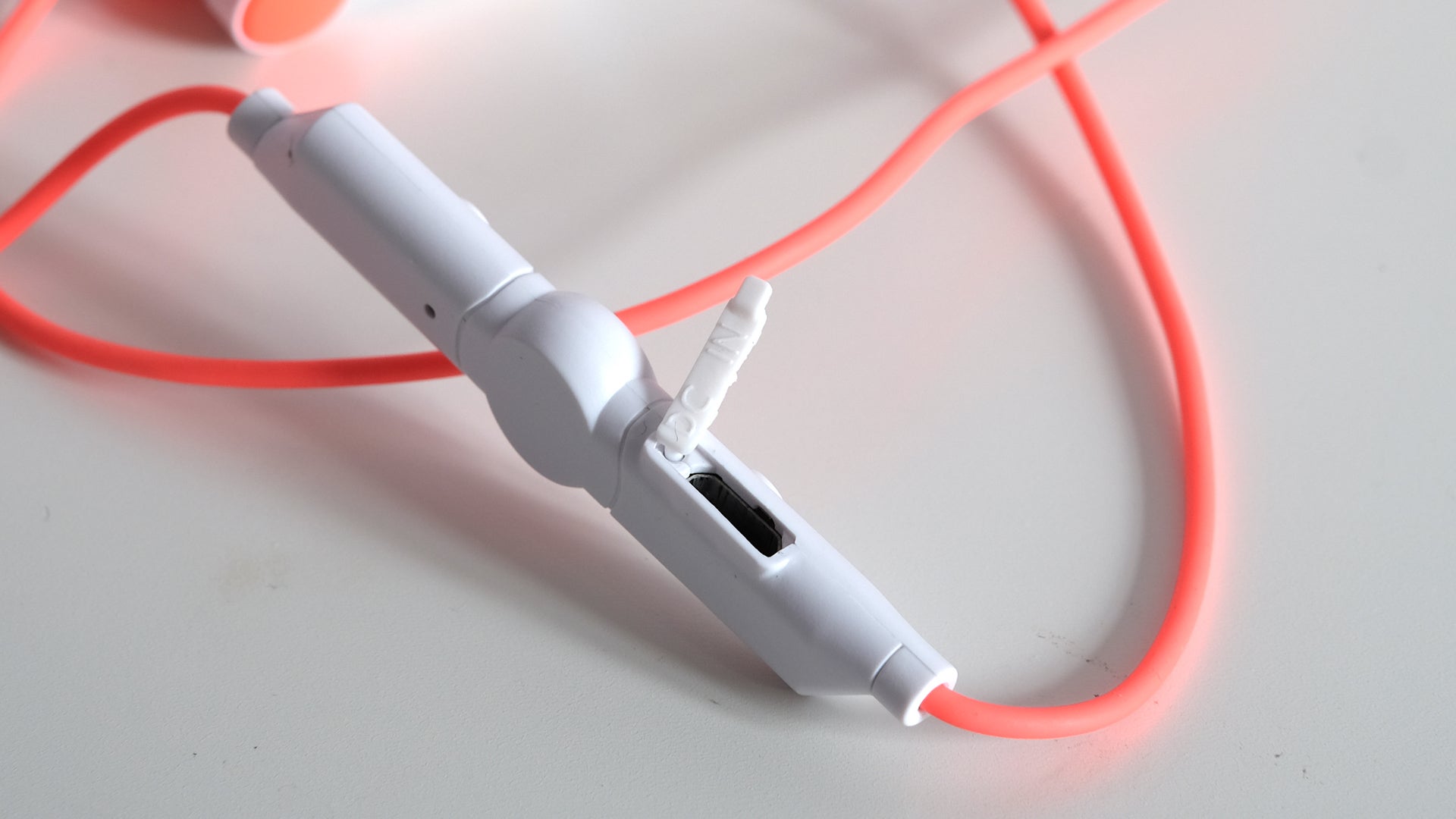Koss Fitbuds BT190i earphones with orange cord on white background.