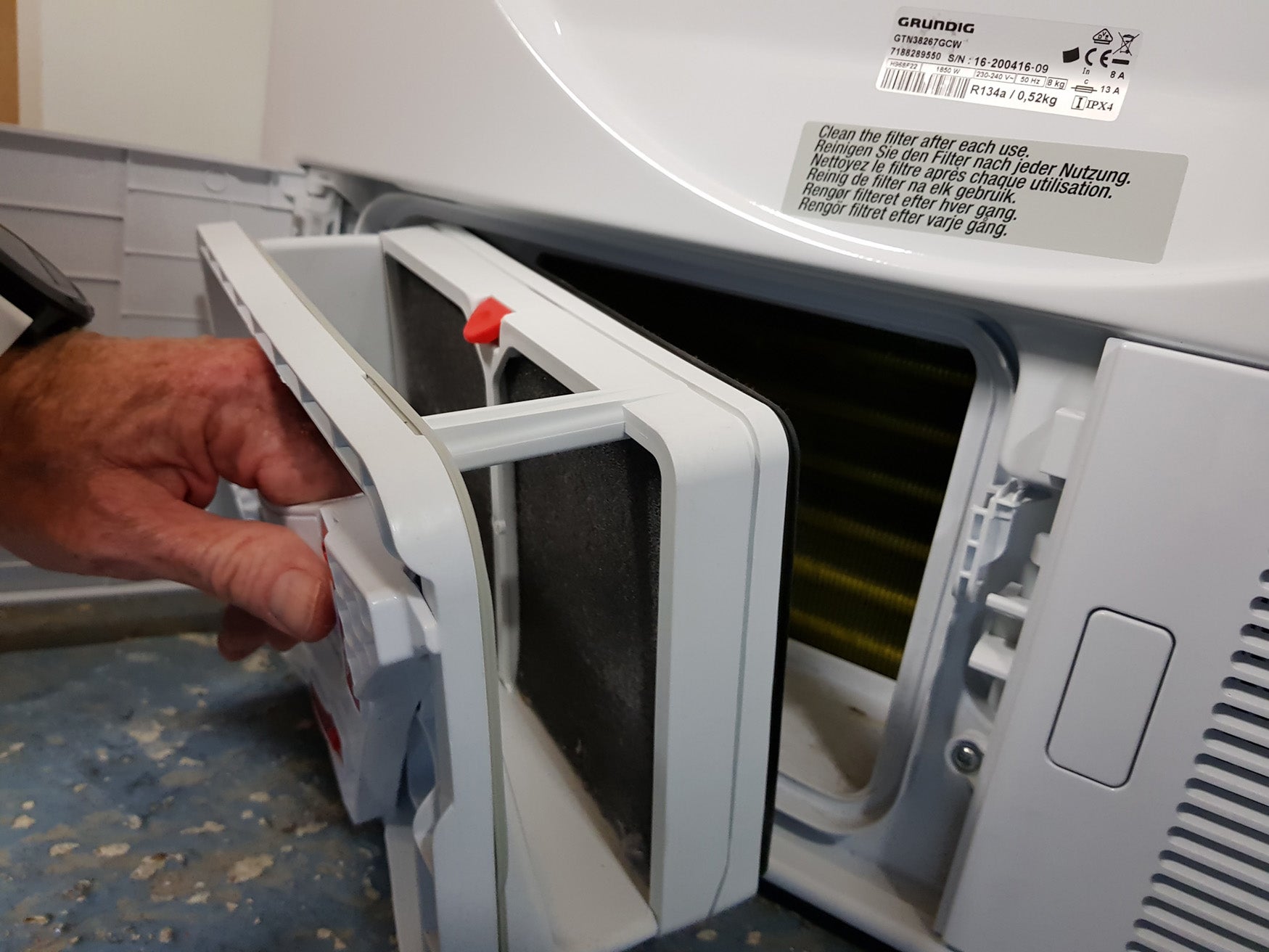 Person cleaning filter of a Grundig GTN38267GCW dryer.