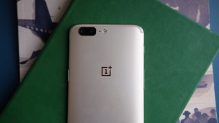 OnePlus 5 smartphone on colored background with dual cameras visible.