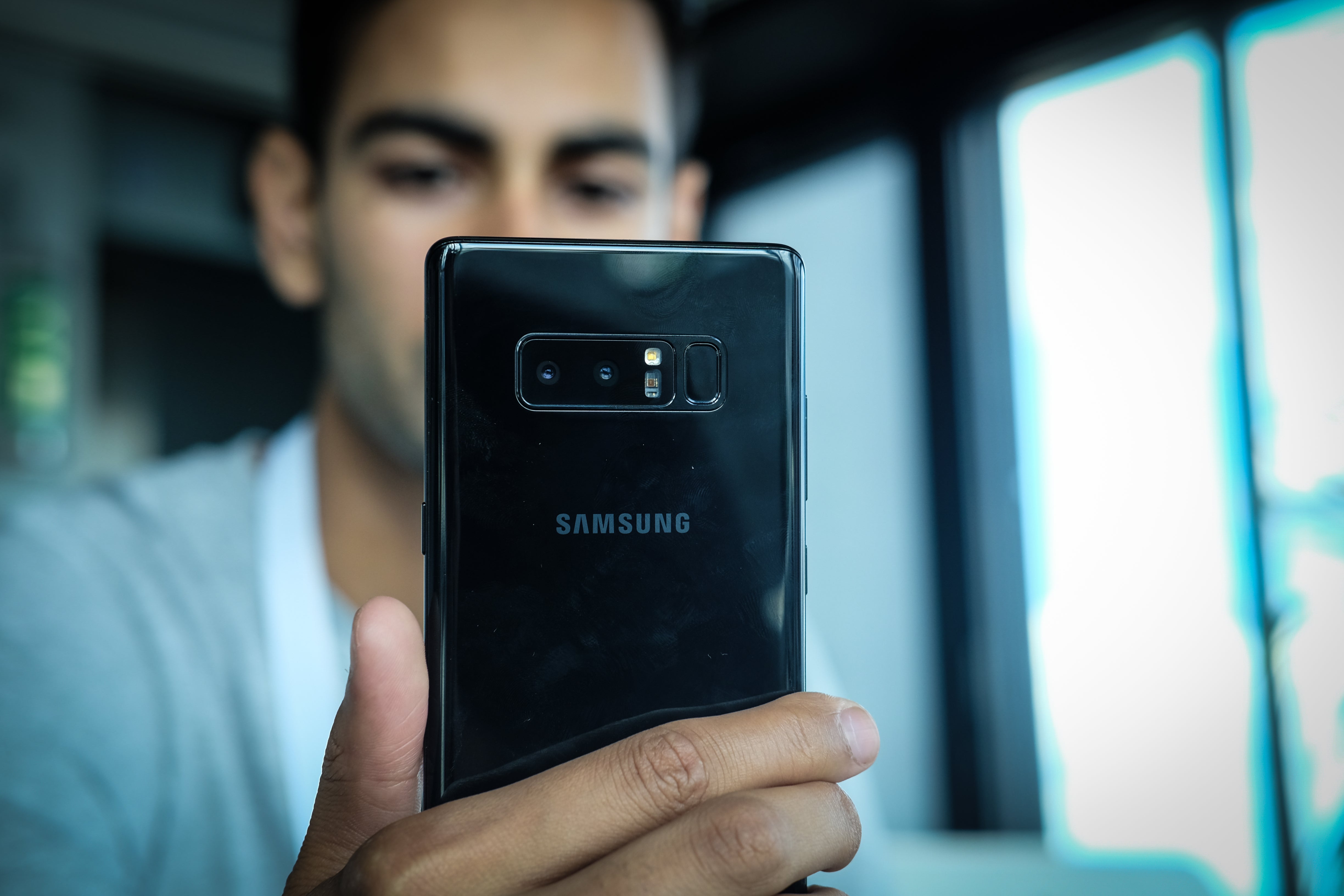Person holding a Samsung Galaxy Note 8 smartphone.