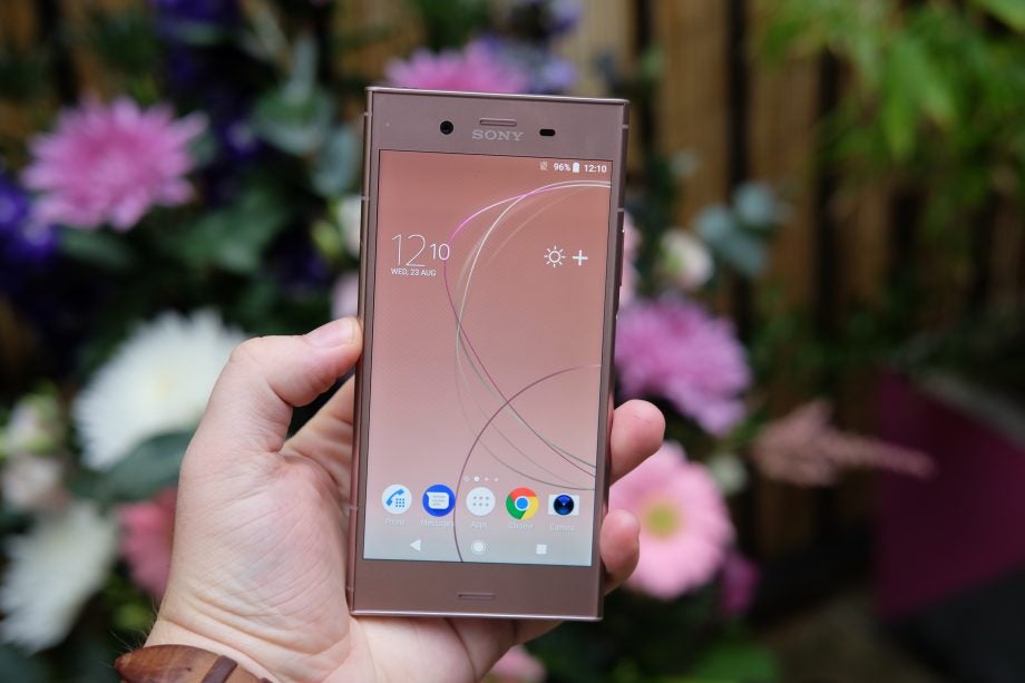 Hand holding Sony Xperia XZ1 smartphone with home screen displayed.