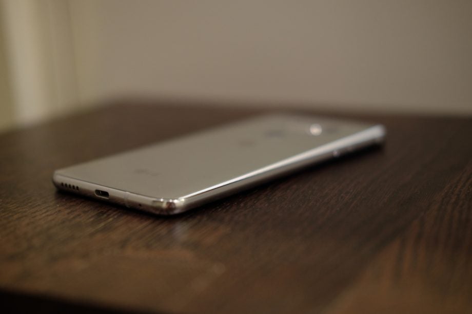 LG V30 smartphone on a wooden surface in soft focus.
