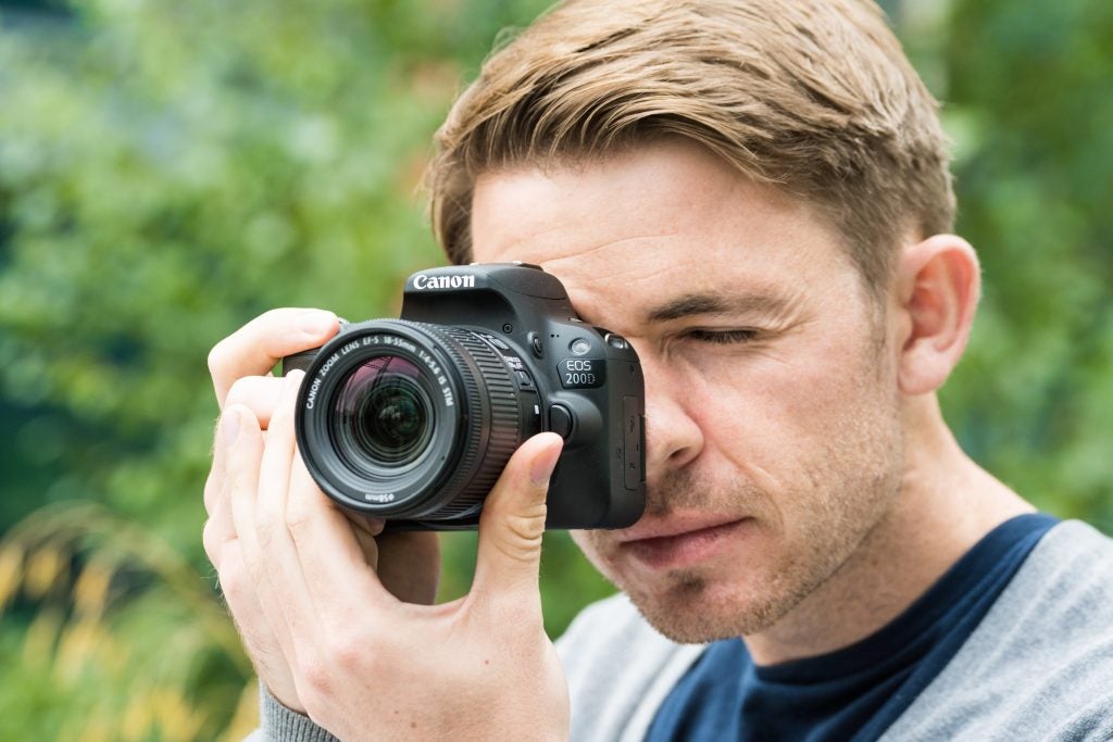 Man taking a photo with a Canon EOS 200D camera.