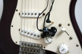Fender FXA2 in-ear monitors on white electric guitar.