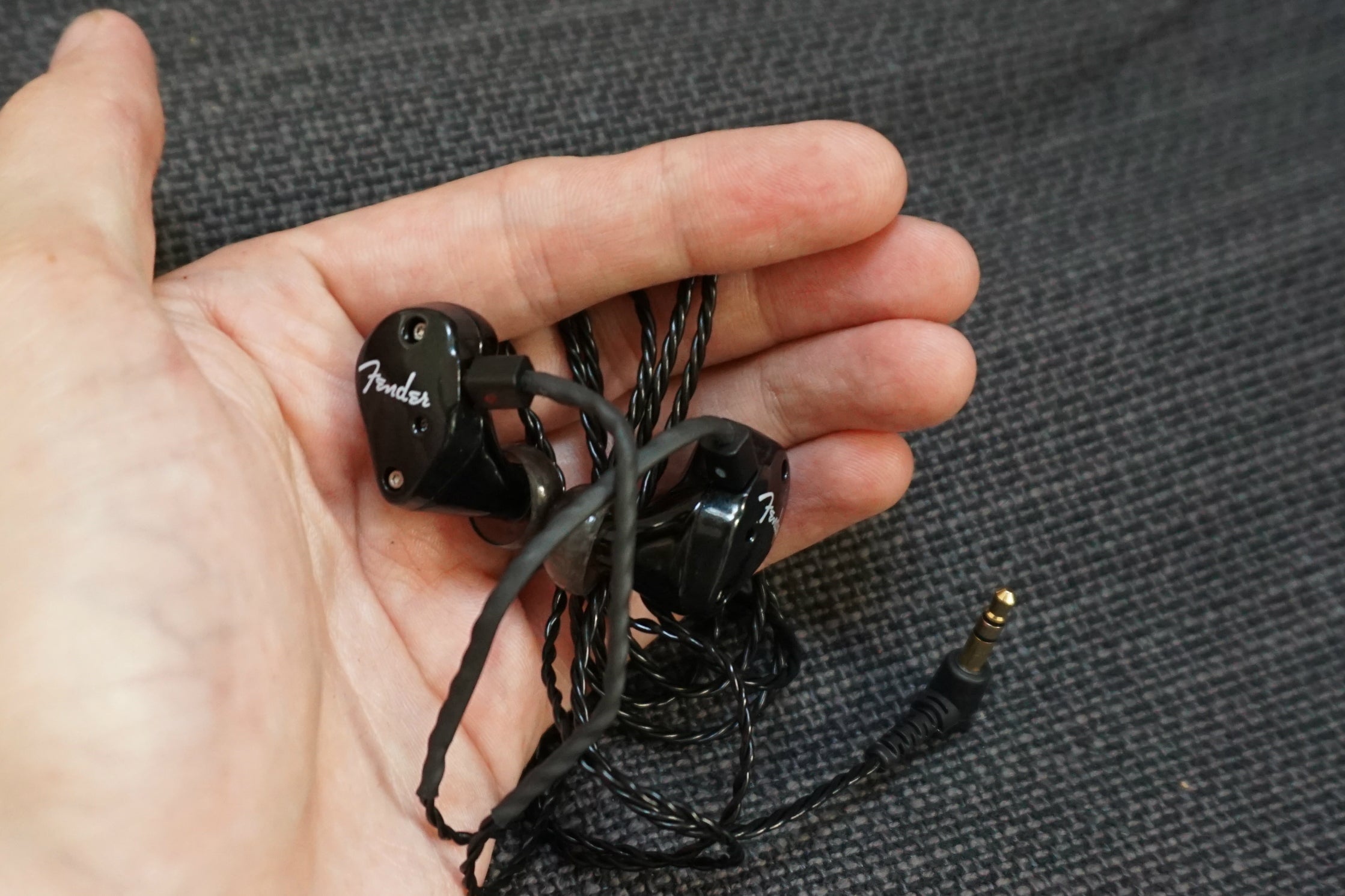 Fender FXA2 in-ear monitors held in a person's palm.