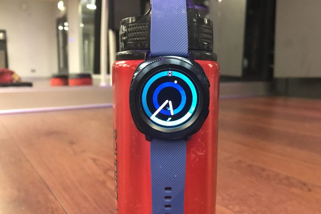 Samsung Gear Sport smartwatch on red surface with blue strap.