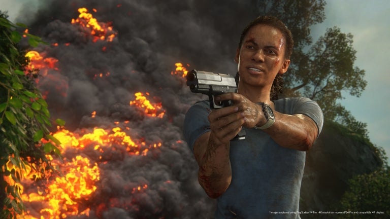Character aiming a gun with fire in the background from Uncharted: The Lost Legacy.