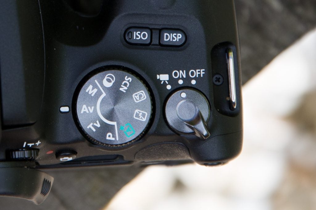 Canon EOS 200D camera showing mode dial and power switch.