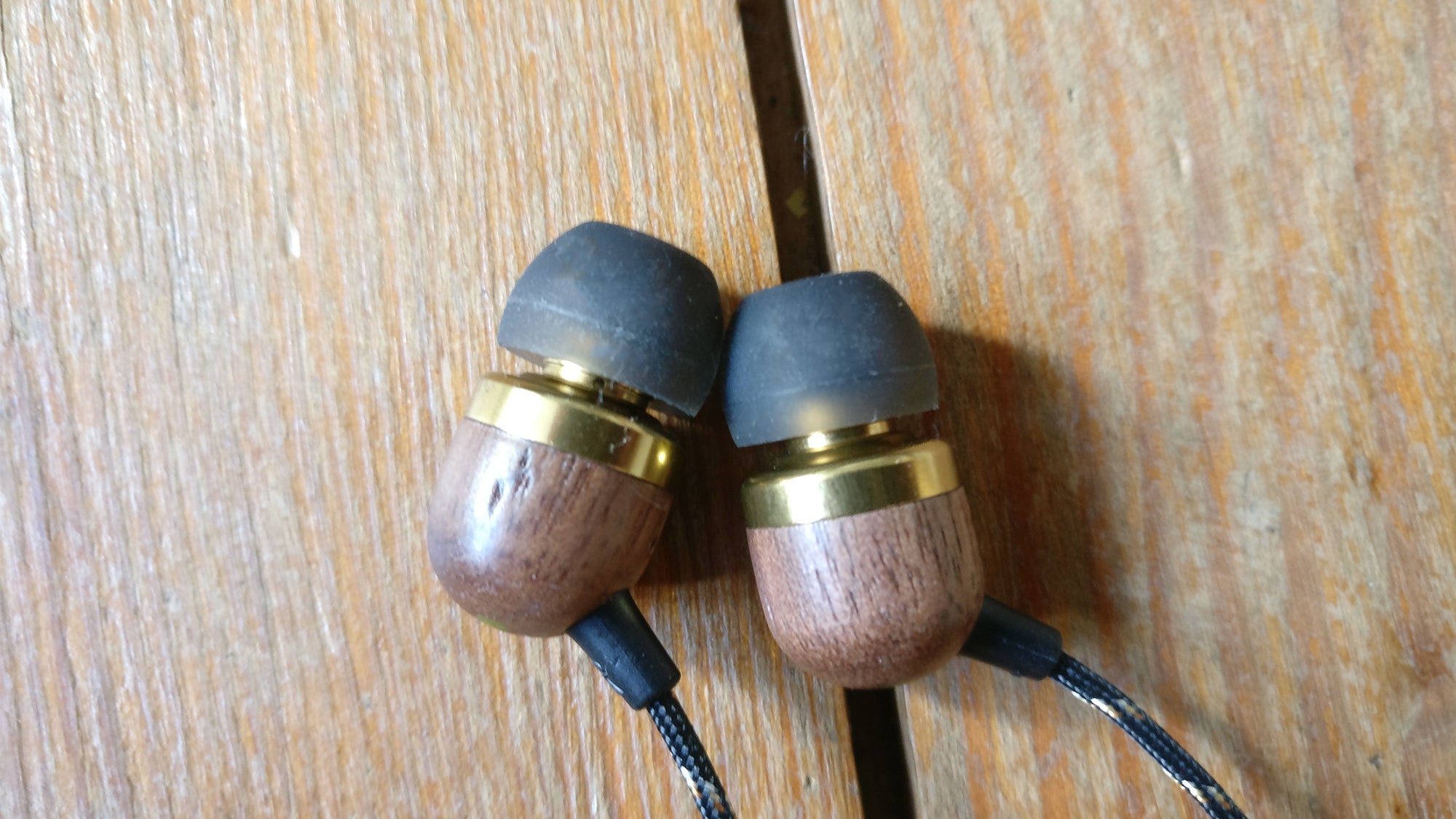 House of Marley Smile Jamaica Wireless earbuds on wooden surface.