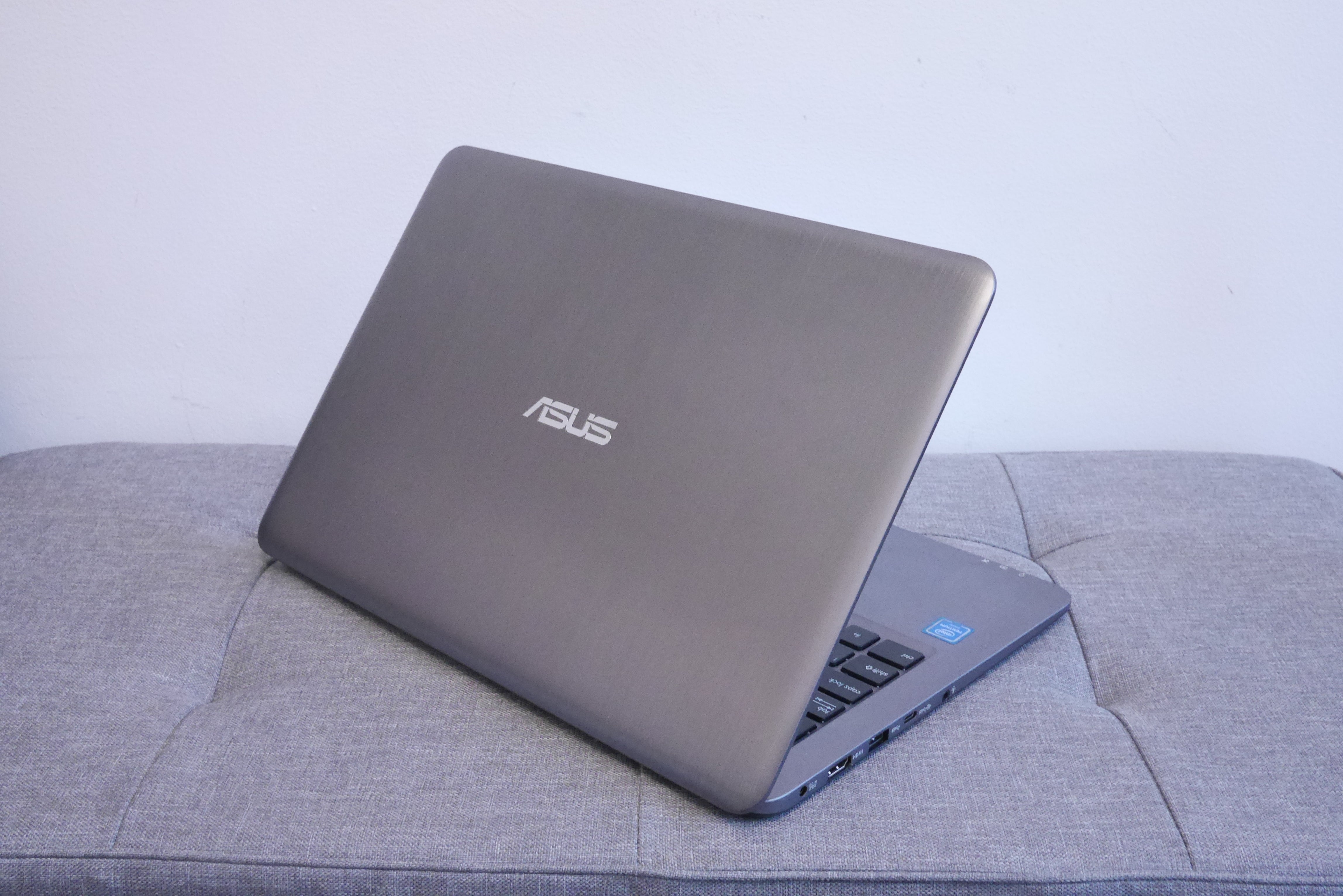 Asus VivoBook L403 laptop on a grey couch.