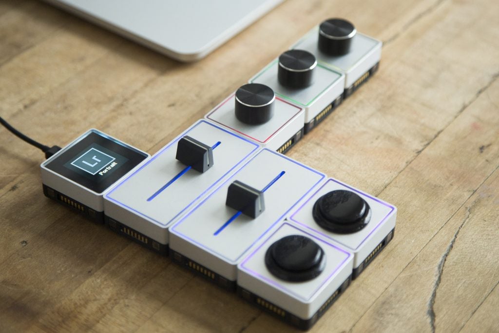 Palette Gear modular controllers on wooden desk next to laptop.