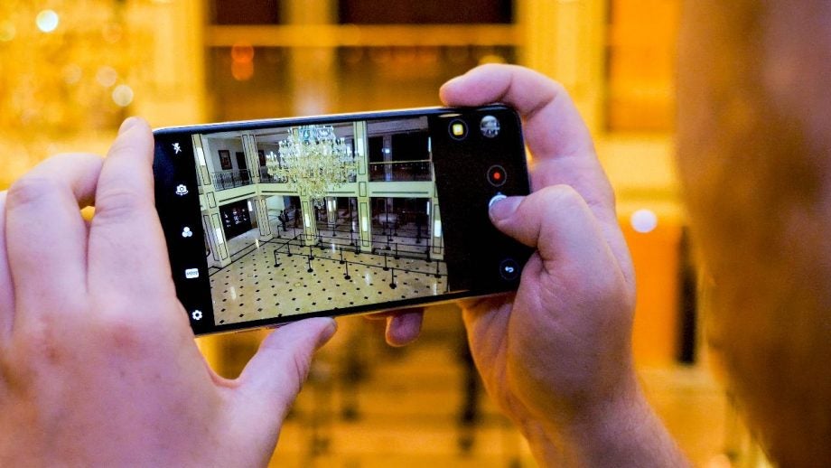 Person capturing ballroom photo with LG V30 smartphone camera.