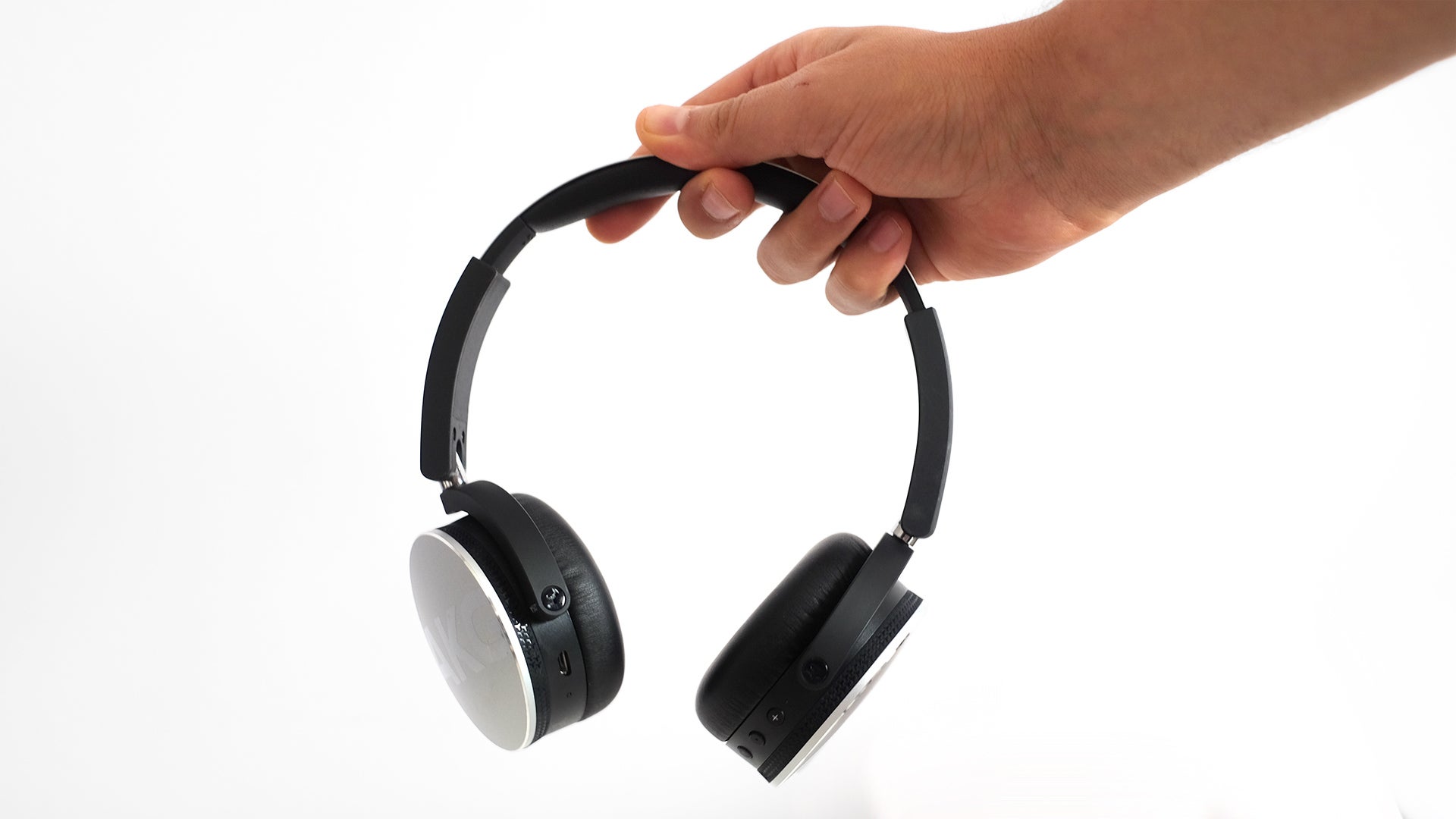 Hand holding black AKG Y50BT wireless headphones.Hand holding black AKG Y50BT wireless headphones against white background.