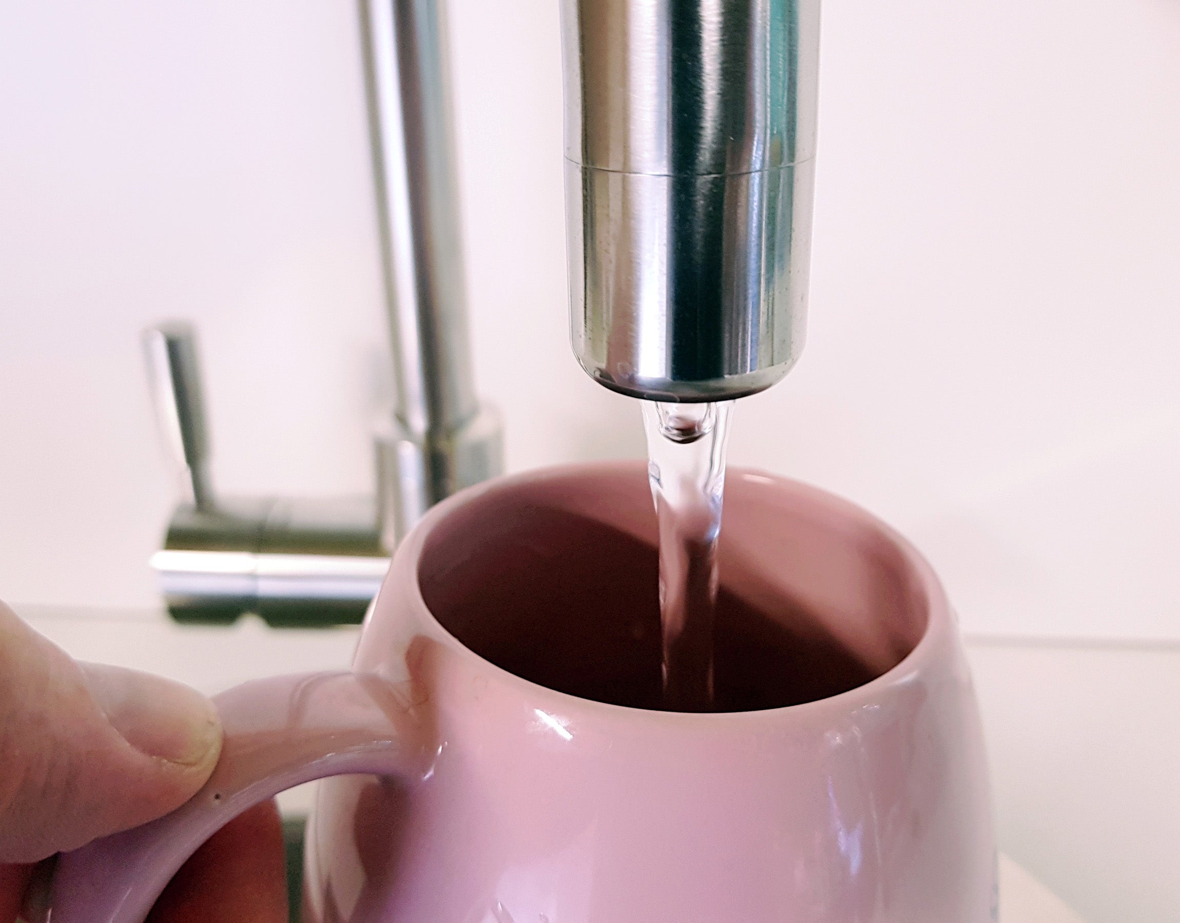 Boiling water pouring from Franke tap into a pink mug.