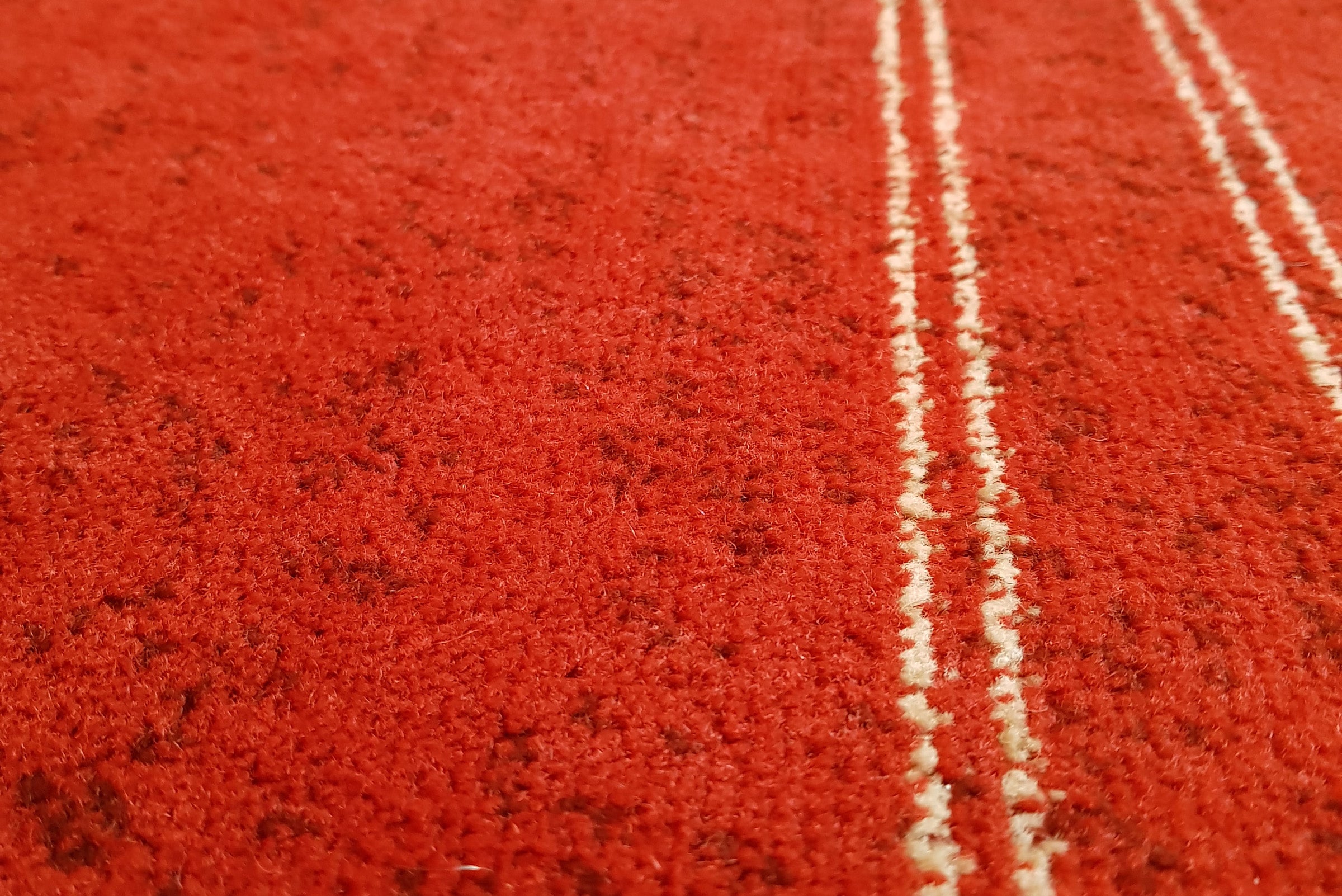 Close-up of clean red carpet with vacuum lines.