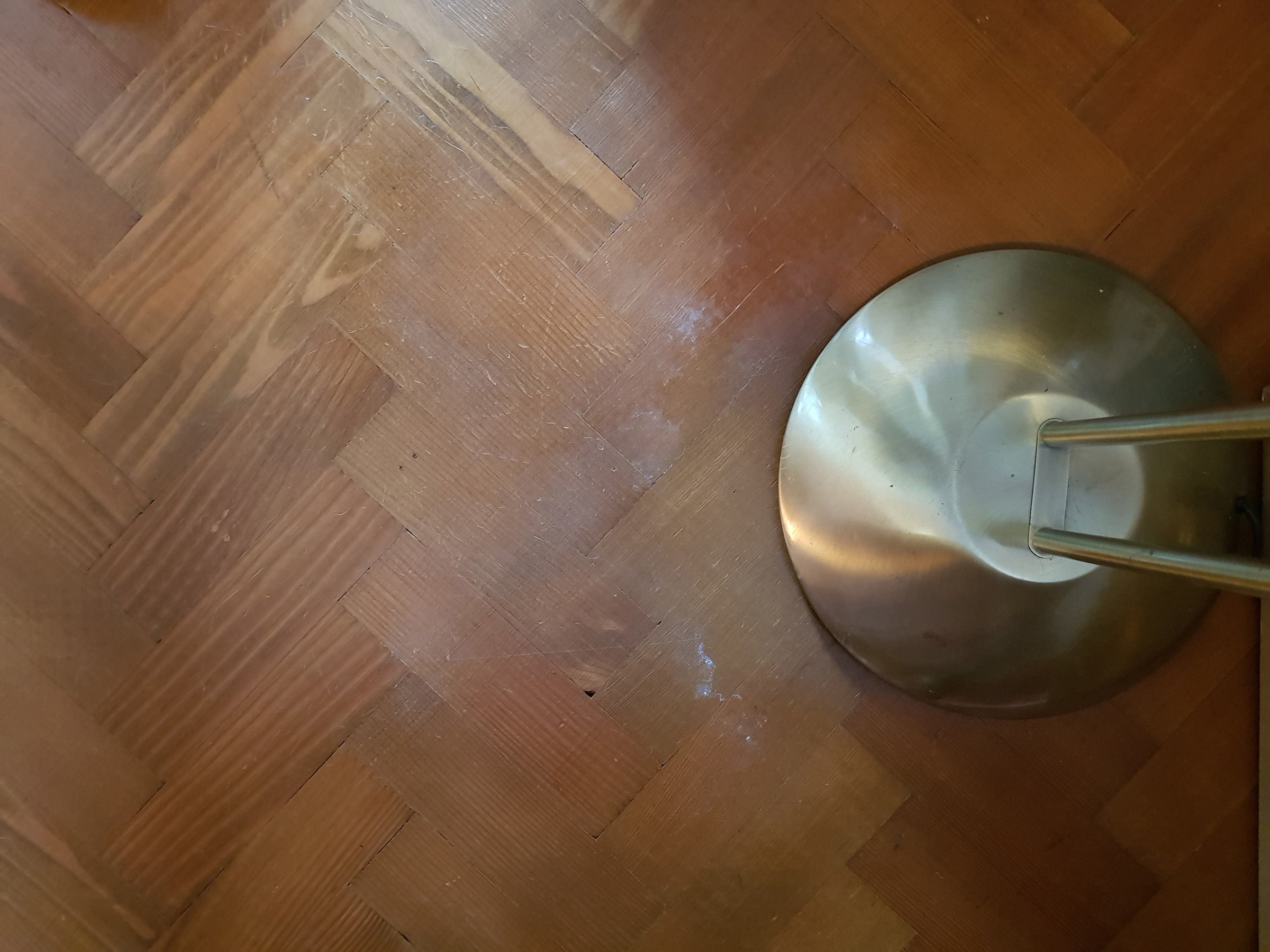 Roomba vacuum under a chair on a wooden floor.
