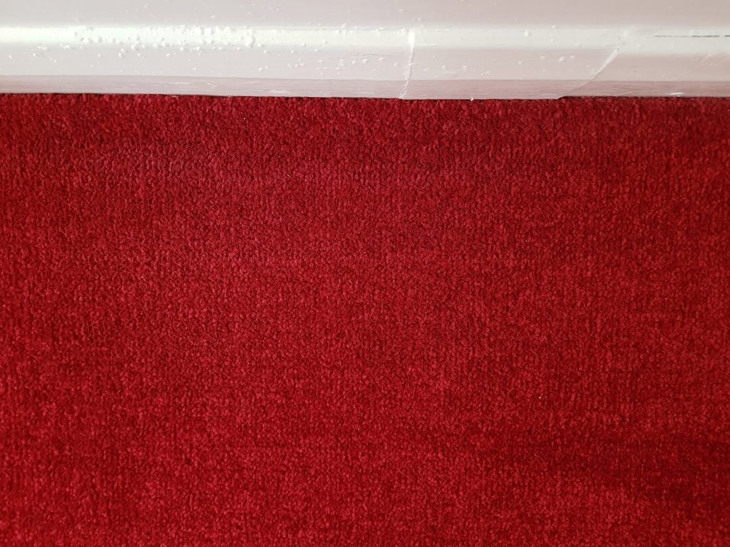 Clean red carpet texture with baseboard.