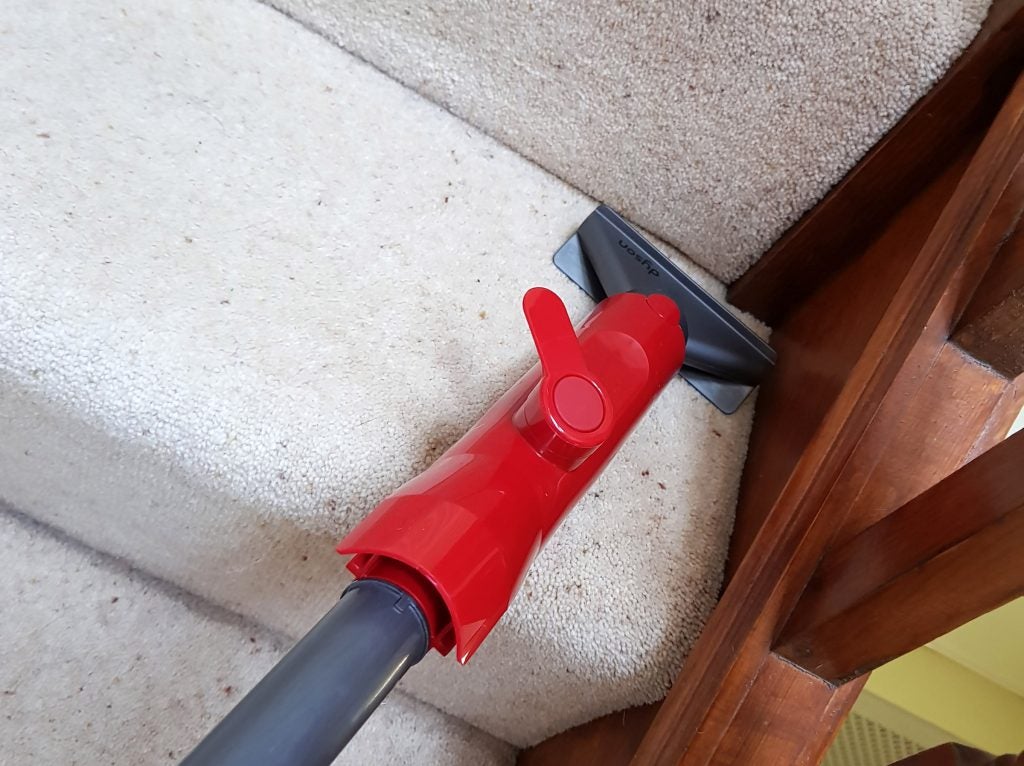 Dyson Light Ball vacuum cleaning a carpeted staircase.