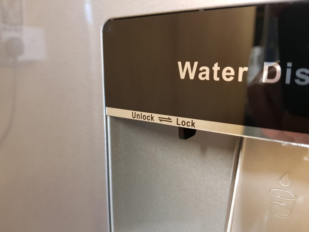 Close-up of a Hisense fridge water dispenser with lock and unlock icons.