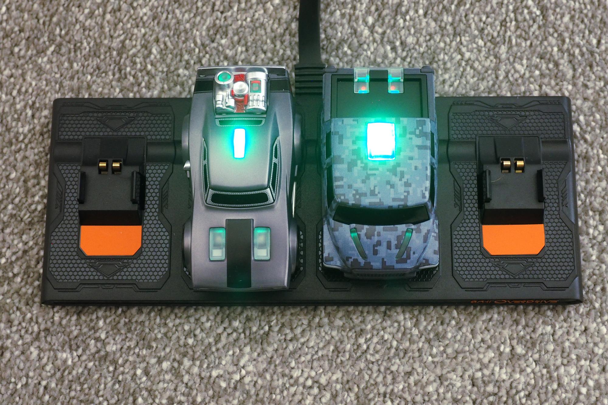 Anki Overdrive cars on charger with illuminated indicators.